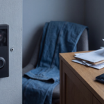 Video doorbell mounted beside a front door with a smartphone showing the doorbell app on a table nearby