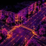 LiDAR point cloud of a city intersection at night, with buildings, trees and crosswalks drawn in glowing purple and orange dots.